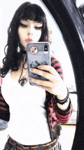 a girl is taking a selfie in front of a mirror with a no smoking sign on her phone