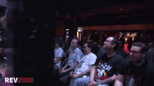 a group of people sitting in a dark room with dev pro written on the bottom right