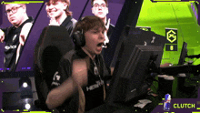 a man wearing headphones is sitting in front of a computer with the word clutch on the bottom right