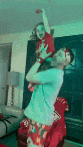 a man holds a little girl up in the air while wearing a shirt with the word city on it