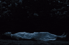 a woman in a white dress is laying in the dark