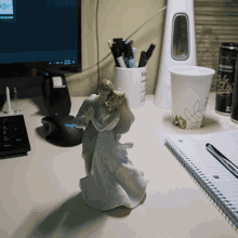 a statue of a bride and groom on a desk next to a cup that says pale ale