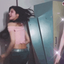 a woman in a pink top is dancing in a locker room