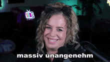 a woman is smiling in front of a microphone with the words " massiv unangenehm " on the bottom right