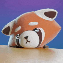 a stuffed animal that looks like a fox is laying on a table