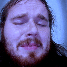 a man with a beard and long hair is crying