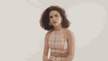 a woman 's hair is blowing in the wind while wearing a pink plaid top