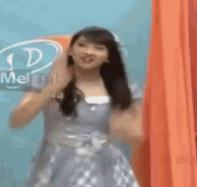 a woman in a purple dress is dancing in front of a sign that says ' meiji ' on it .