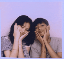 a boy and a girl posing for a picture with their hands on their face