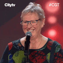 a woman wearing glasses is smiling in front of a microphone with the hashtag #cgt