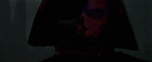 a close up of a person 's face in a dark room with a red light behind them .