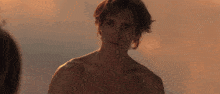 a man without a shirt is looking at another person