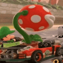 a toy car with a plant on top of it is driving down a race track .