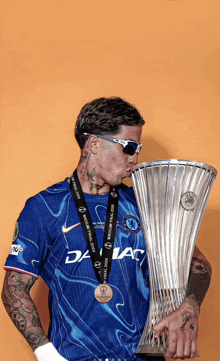 a man wearing sunglasses and a blue shirt with the word chelsea on it