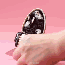 a close up of a person holding an oreo cookie with mr.cakes written on the bottom right