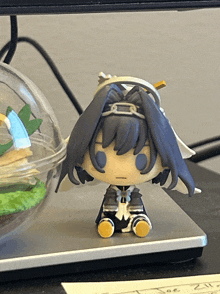 a small figurine sits on a desk next to a note that says " toe "
