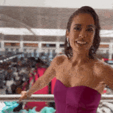 a woman is wearing a purple strapless dress and smiling .