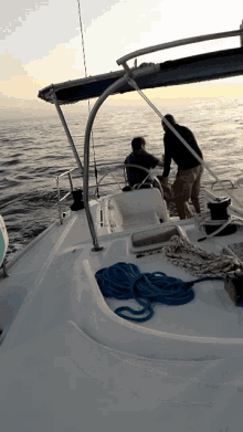 two men on a boat in the ocean with a blue rope on the deck