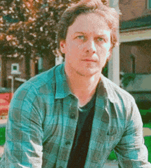 a man in a plaid shirt is sitting on a bench in front of a house .