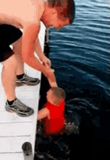 a man holds the hand of a baby who is in the water