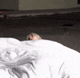 a person is laying on a bed with a white blanket