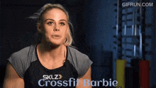 a woman is talking into a microphone in a gym while wearing a black shirt .