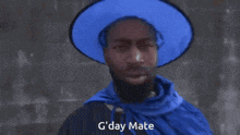 a man with a beard wearing a blue hat and a blue cape says g day mate
