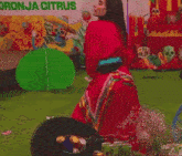 a woman in a red dress is kneeling down in front of a sign that says onja citrus .