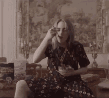a woman in a dress is eating a bowl of cereal with a bag of black stones in the background