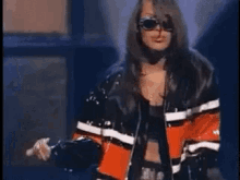 a woman wearing sunglasses and a leather jacket is standing in front of a stage .