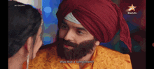 a man with a beard and a red turban talks to a woman with the words was that a compliment on the bottom
