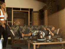 a man laying on a couch with a bottle of corona on a coffee table