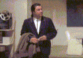 a man in a suit and tie is standing in a room holding a coat .