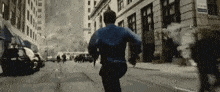 a man in a blue shirt is running down a city street .