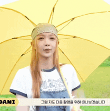 a person holding a yellow umbrella in front of a green field .