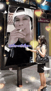 a woman stands in front of a billboard with a picture of a man smoking
