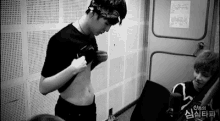 a black and white photo of a young man taking off his shirt .
