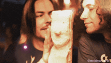 two men are looking at a statue of a man 's face with a watermark that says @meldivararts