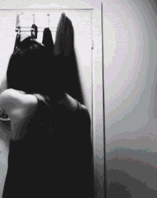 a black and white photo of a woman standing in front of a closet