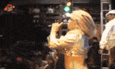 a woman singing into a microphone in front of a sign that says ' extra '