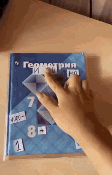 a person 's hand is reaching out towards a book that says ' geometry ' on it