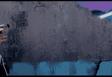 a man with blue hair is standing in front of a concrete wall holding a gun .