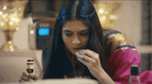 a woman is sitting at a table with a bottle of alcohol in her hand and eating food .