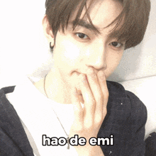 a young man covering his mouth with his hands and the words hao de emi written below him