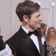 a man in a tuxedo has a sign that says vogue in front of him