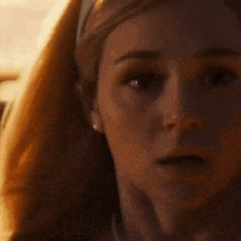 a close up of a woman 's face wearing a necklace and headband .