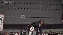 a female wrestler is jumping in the air in front of a stardom banner