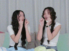 two young women are sitting on a couch making funny faces .