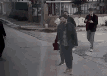 a group of people are walking down a street and one of them is holding a red hat