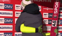 a person hugging another person in front of a wall that says omv and sport 2000